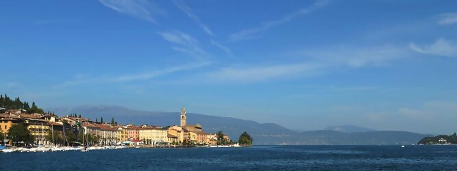 Trip Schweiz beliebte Urlaubsziele am Gardasee -  Mit einer Fläche von 370 km² ist der Gardasee der größte See Italiens. Es liegt am Fuße der Alpen und erstreckt sich über drei Staaten: Lombardei, Venetien und Trentino. Die maximale Tiefe des Sees beträgt 346 m, er hat eine längliche Form und sein nördliches Ende ist sehr schmal. Dort ist der See von den Bergen der Gruppo di Baldo umgeben. Du trittst aus deinem gemütlichen Hotelzimmer und es begrüßt dich die warme italienische Sonne. Du blickst auf den atemberaubenden Gardasee, der in zahlreichen Blautönen schimmert - von tiefem Dunkelblau bis zu funkelndem Türkis. Majestätische Berge umgeben dich, während die Brise sanft deine Haut streichelt und der Duft von blühenden Zitronenbäumen deine Nase kitzelt. Du schlenderst die malerischen, engen Gassen entlang, vorbei an farbenfrohen, blumengeschmückten Häusern. Vereinzelt unterbricht das fröhliche Lachen der Einheimischen die friedvolle Stille. Du fühlst dich wie in einem Traum, der nicht enden will. Jeder Schritt führt dich zu neuen Entdeckungen und Abenteuern. Du probierst die köstliche italienische Küche mit ihren frischen Zutaten und verführerischen Aromen. Die Sonne geht langsam unter und taucht den Himmel in ein leuchtendes Orange-rot - ein spektakulärer Anblick.